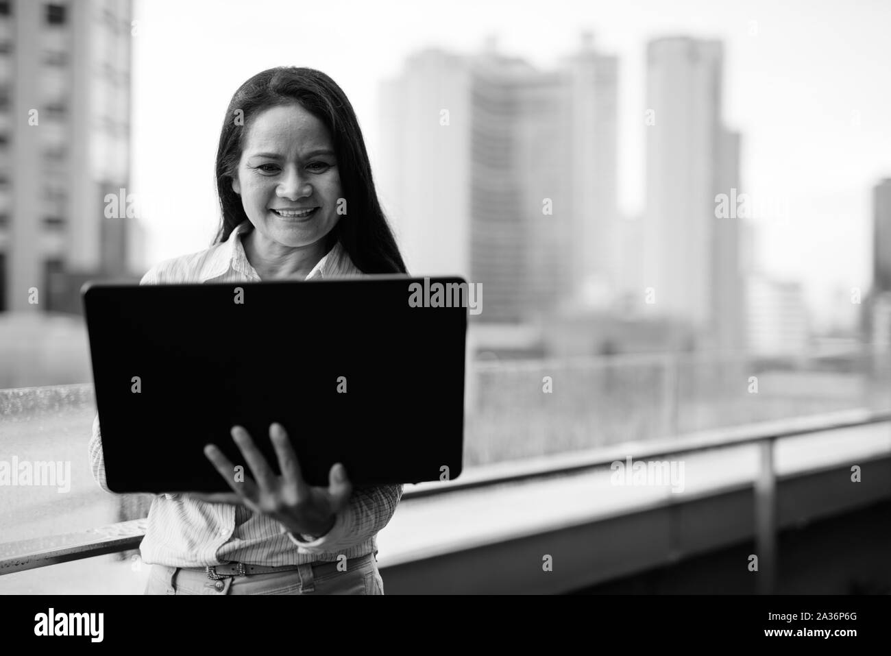 Mature Asian businesswoman using laptop computer in city Banque D'Images