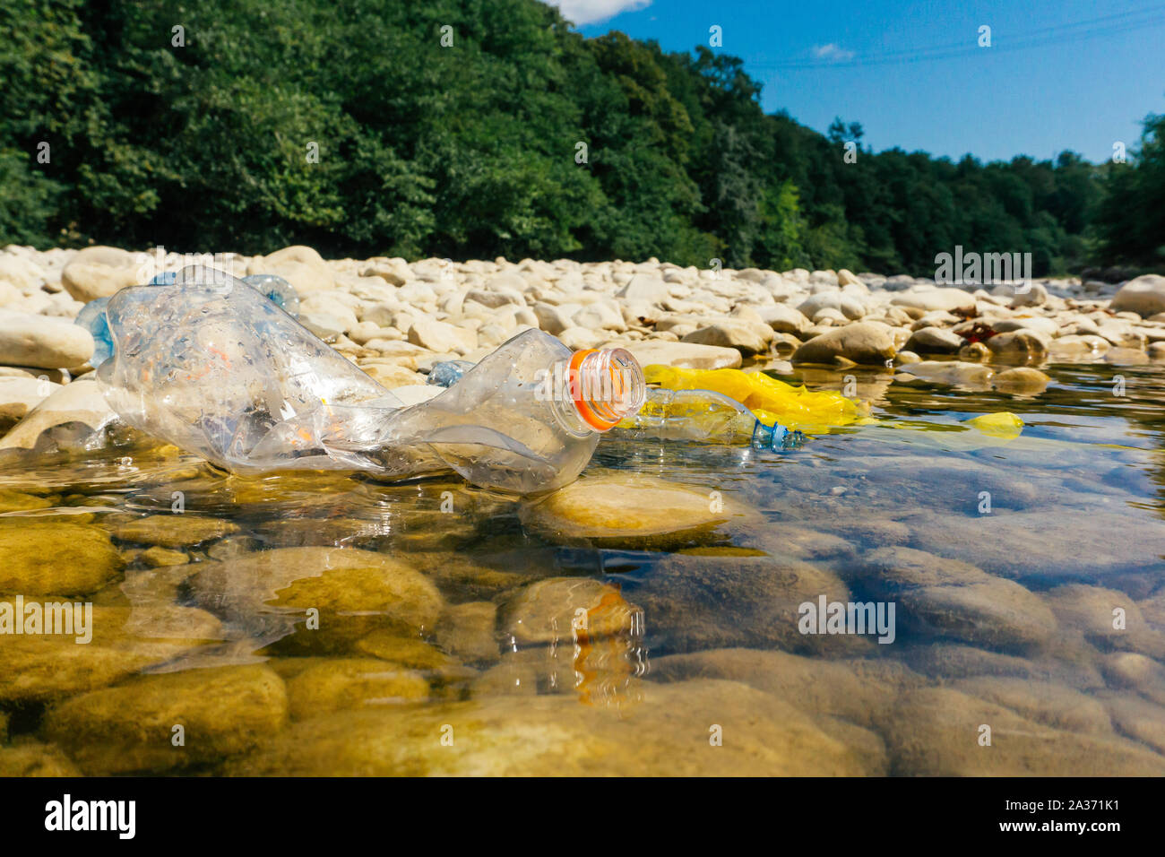 La pollution en plastique dans la rivière. Sacs et bouteilles en ...