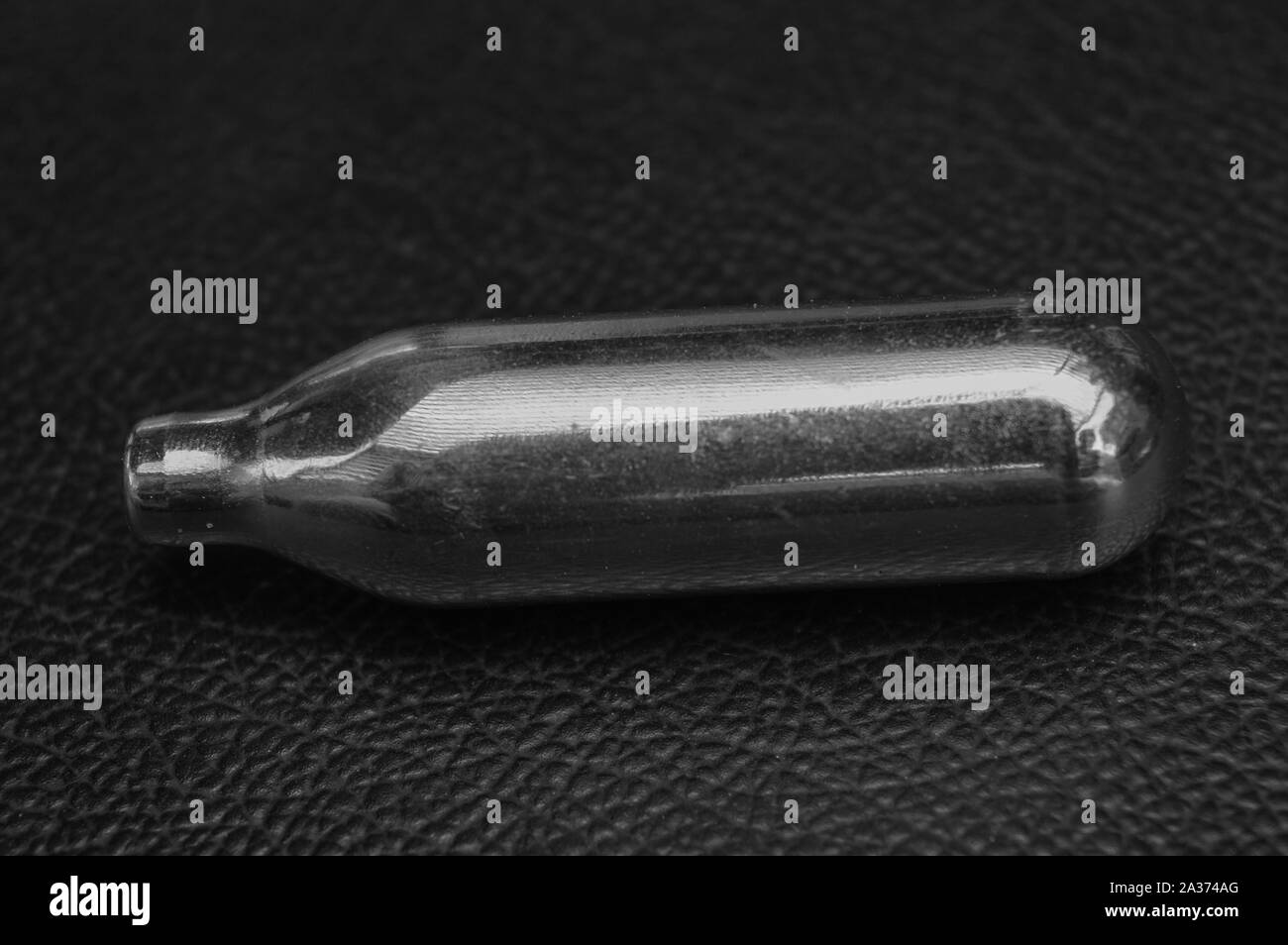 Une petite bouteille de gaz isolé sur table en cuir noir. Banque D'Images