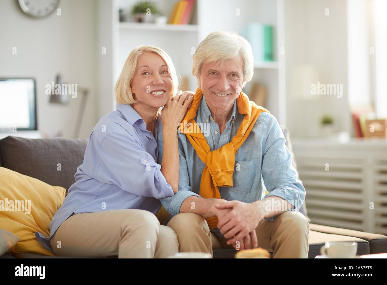Portrait of happy senior couple looking at camera tout en embrassant amoureusement et profiter de week-end à la maison, copy space Banque D'Images