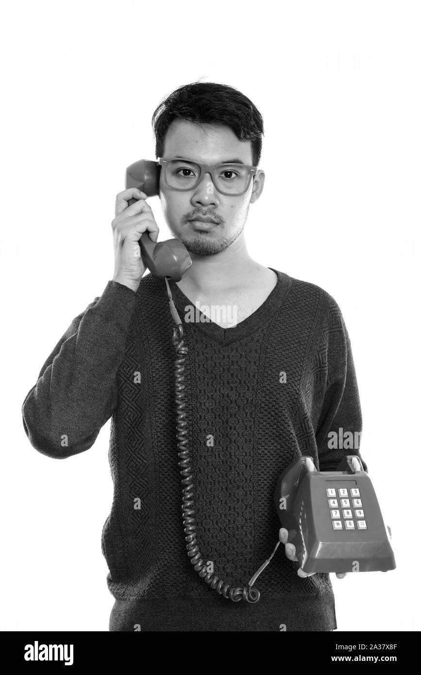 Studio shot of young Asian man talking on old telephone Banque D'Images