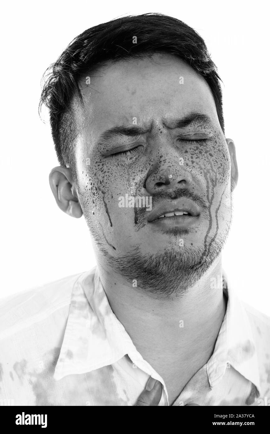 Visage de jeune homme asiatique fou à la triste avec les yeux fermés et le sang sur le visage Banque D'Images