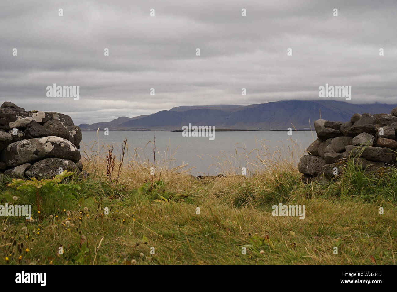 Une ouverture dans un vieux mur de pierre montrant une vue sur mer et montagnes brumeuses Banque D'Images