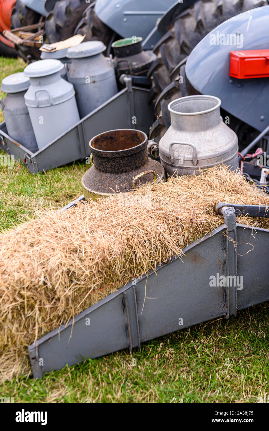 Les bidons de lait et d'une botte de paille à l'arrière d'un tracteur d'époque. Banque D'Images