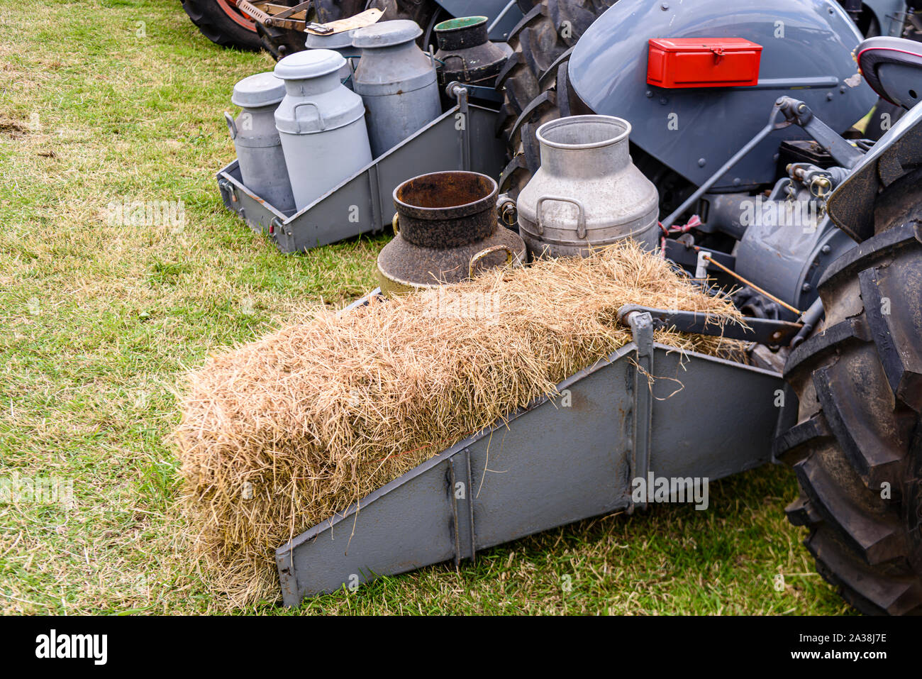 Les bidons de lait et d'une botte de paille à l'arrière d'un tracteur d'époque. Banque D'Images