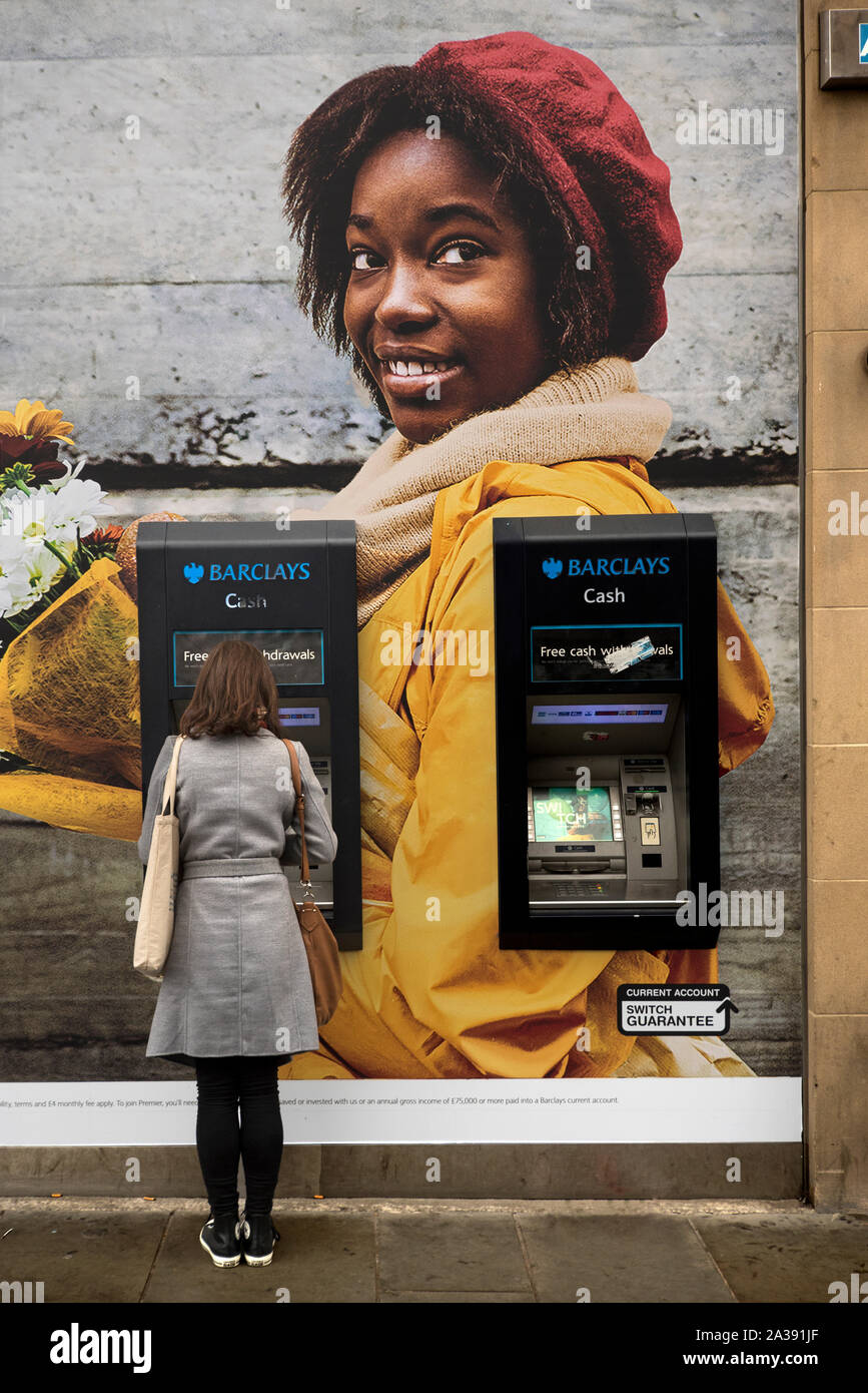 Jeune femme à l'aide d'un client de la Banque Barclays, distributeur automatique de billets sur Princes Street à Édimbourg, Écosse, Royaume-Uni. Banque D'Images