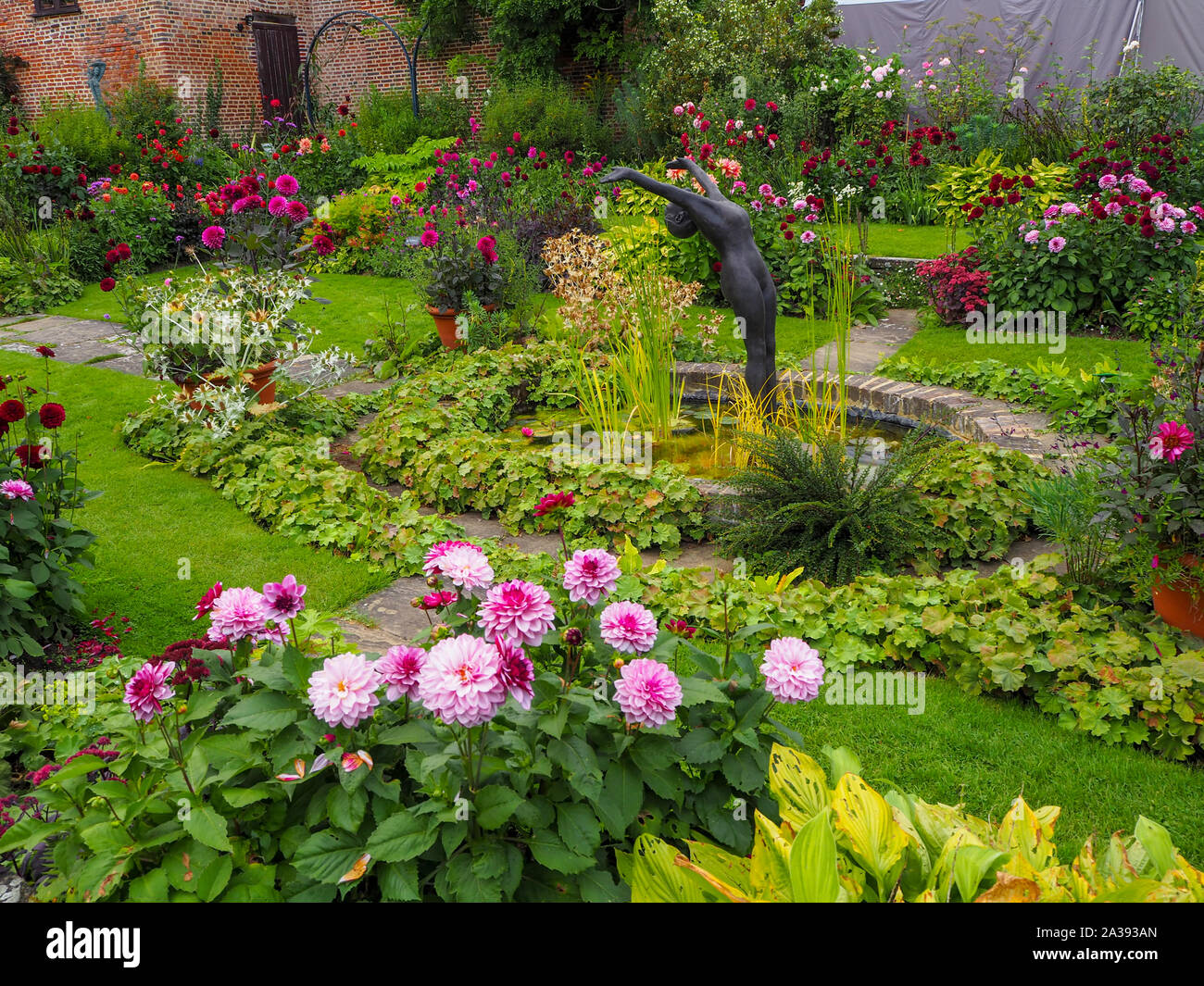 Chenies Manor jardin en contrebas de l'étang ornemental avec Alan Biggs sculpture dans le centre avec Dahlia 'Crème de Cassis', 'Labyrinthe' et divers feuillages. Banque D'Images