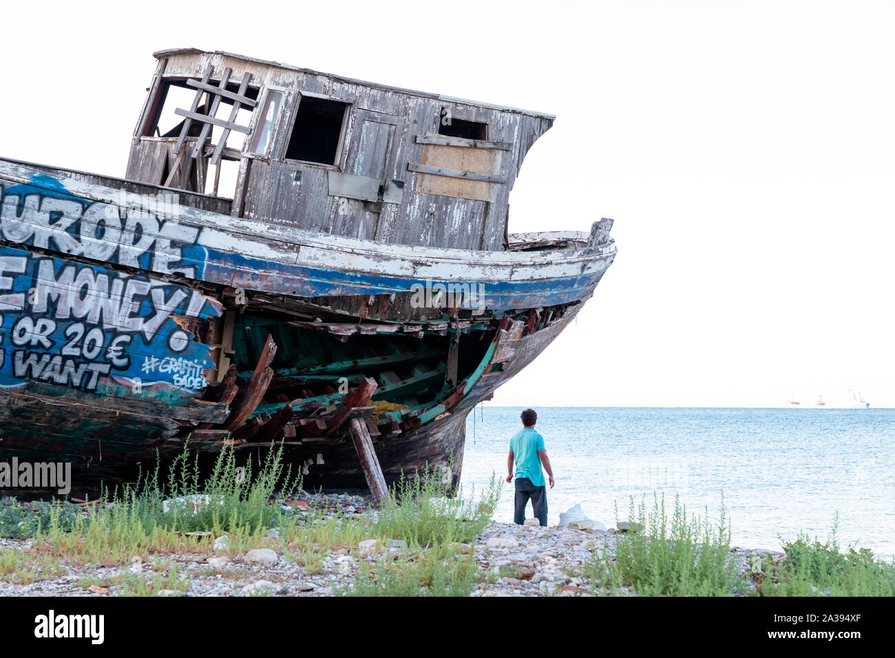 Un vieux bateau de pêche en bois couvert de graffitis sur cale sèche. Banque D'Images