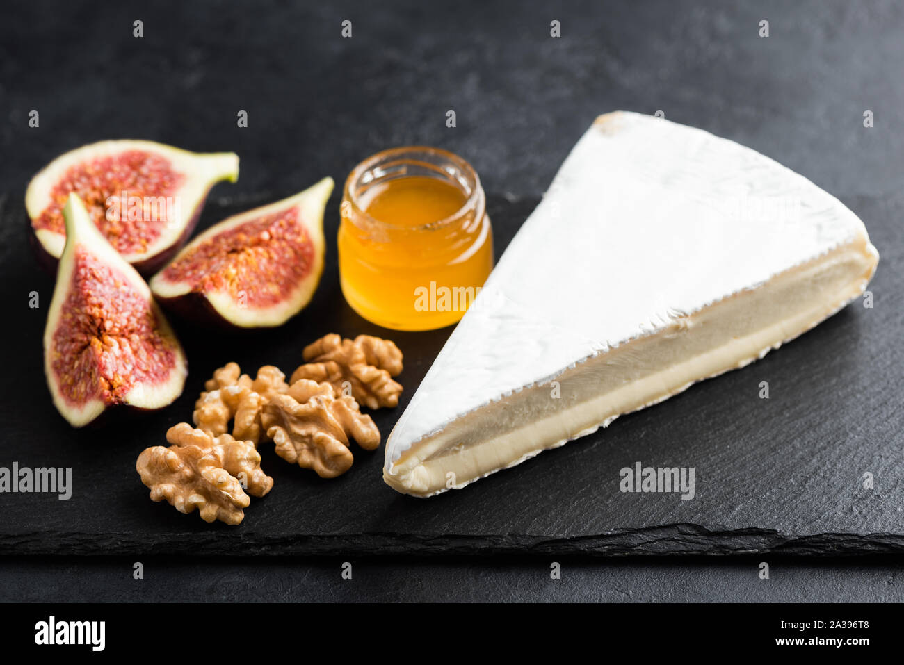 Brie ou camembert aux figues et noix sur fond d'ardoise noire. Plateau de fromages savoureux Banque D'Images