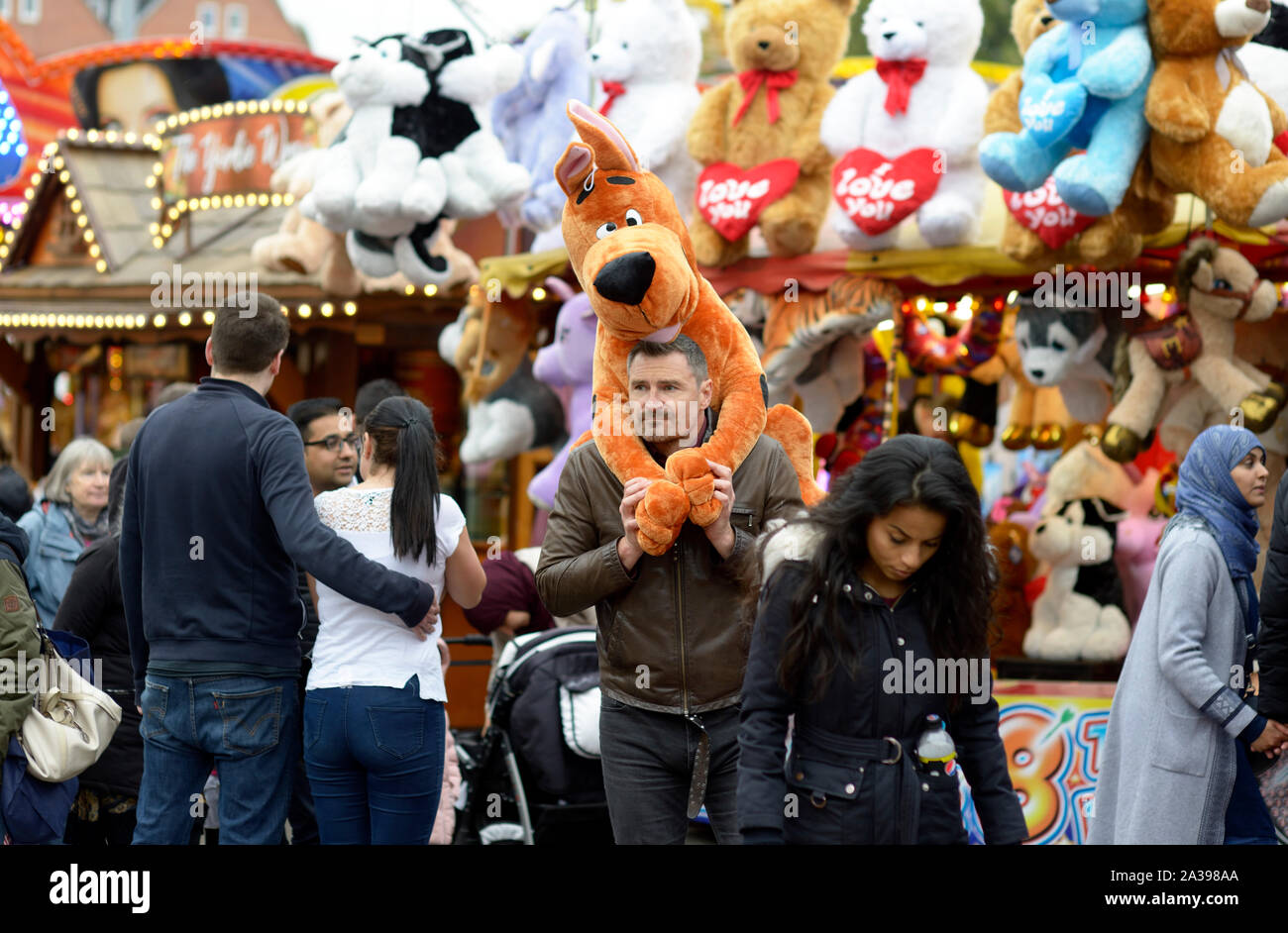 Homme avec furry animal jouet sur ses épaules, à Goose Fair, Nottingham Banque D'Images