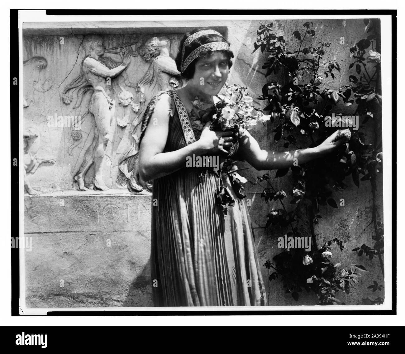 Scène du film muet les derniers jours de Pompéi montrant une jeune femme tenant des fleurs à Sa poitrine alors qu'elle choisit une rose, bas-reliefs de l'arrière-plan Banque D'Images