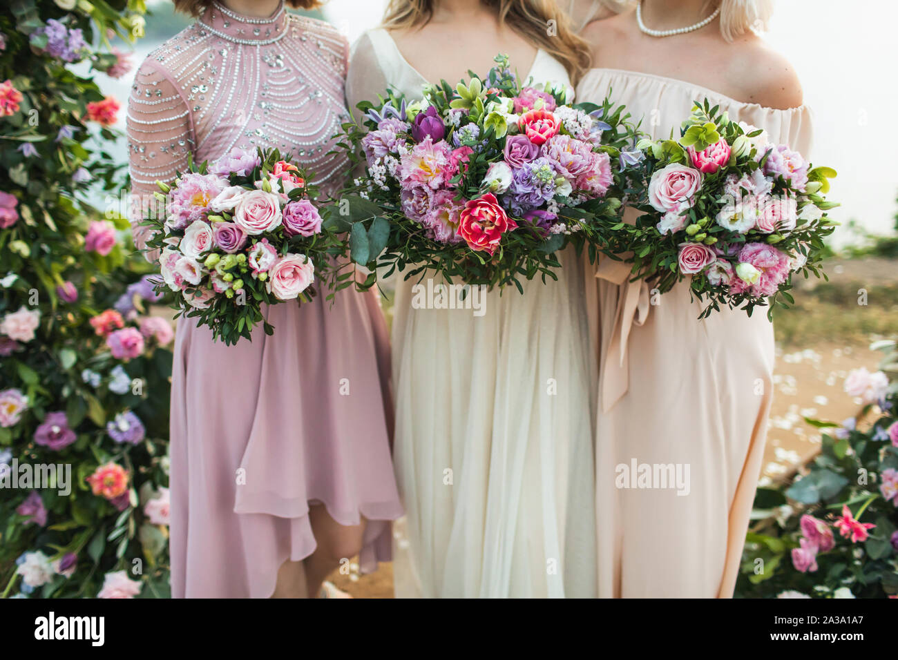 Trois demoiselles tenant dans les mains de beaux bouquets de fleurs avec du  rouge, rose, violet, les pivoines, les roses, les tulipes. Style de mariage  moderne et branché Photo Stock - Alamy