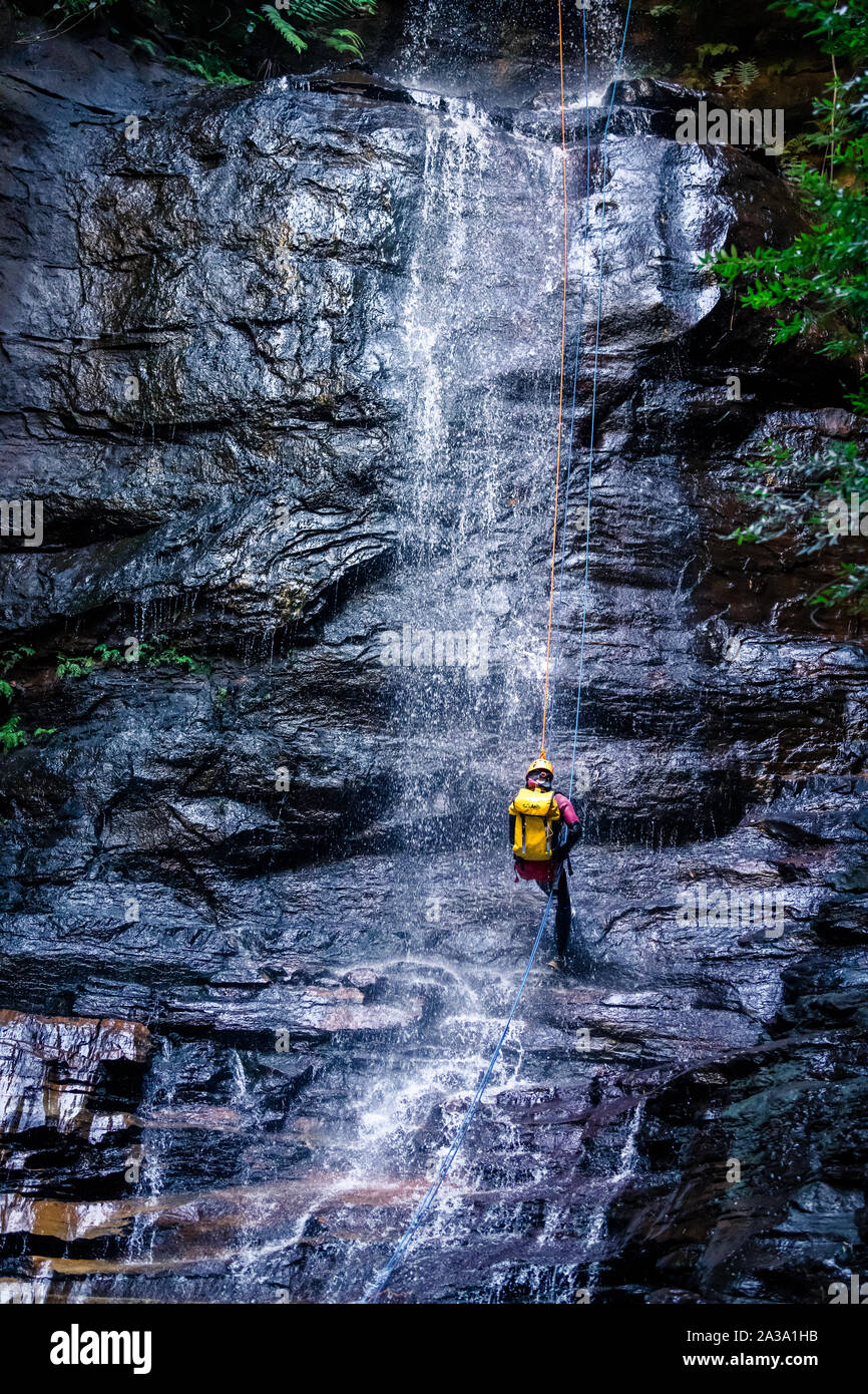L'impératrice Falls, Blue Mountains, Australie - 7 Sept 2019 : l'Homme descend long drop cascade sur roches glissantes, le port de sac à dos, avec ro Banque D'Images