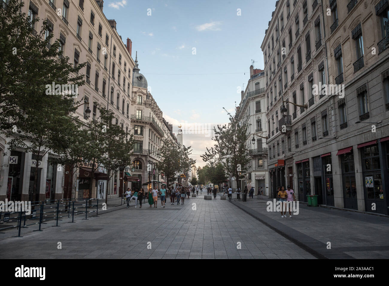 LYON, FRANCE - 14 juillet 2019 : Les piétons circulant sur la rue de la République à Lyon, France, à la tombée de la face à des bâtiments de style Haussmannien et commer Banque D'Images