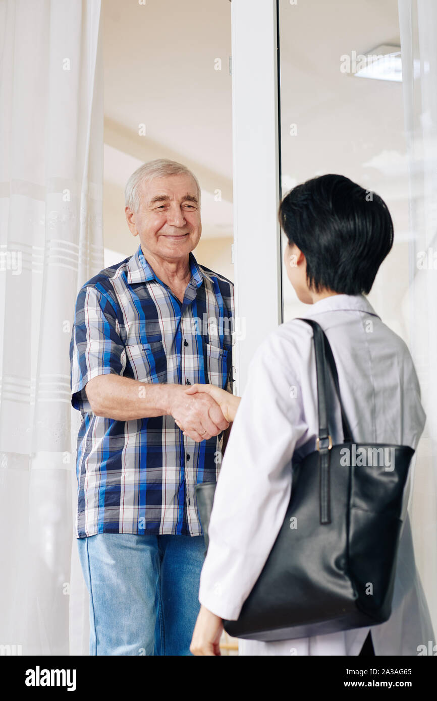 Smiling senior man shaking part du médecin qui est en visite à la maison Banque D'Images