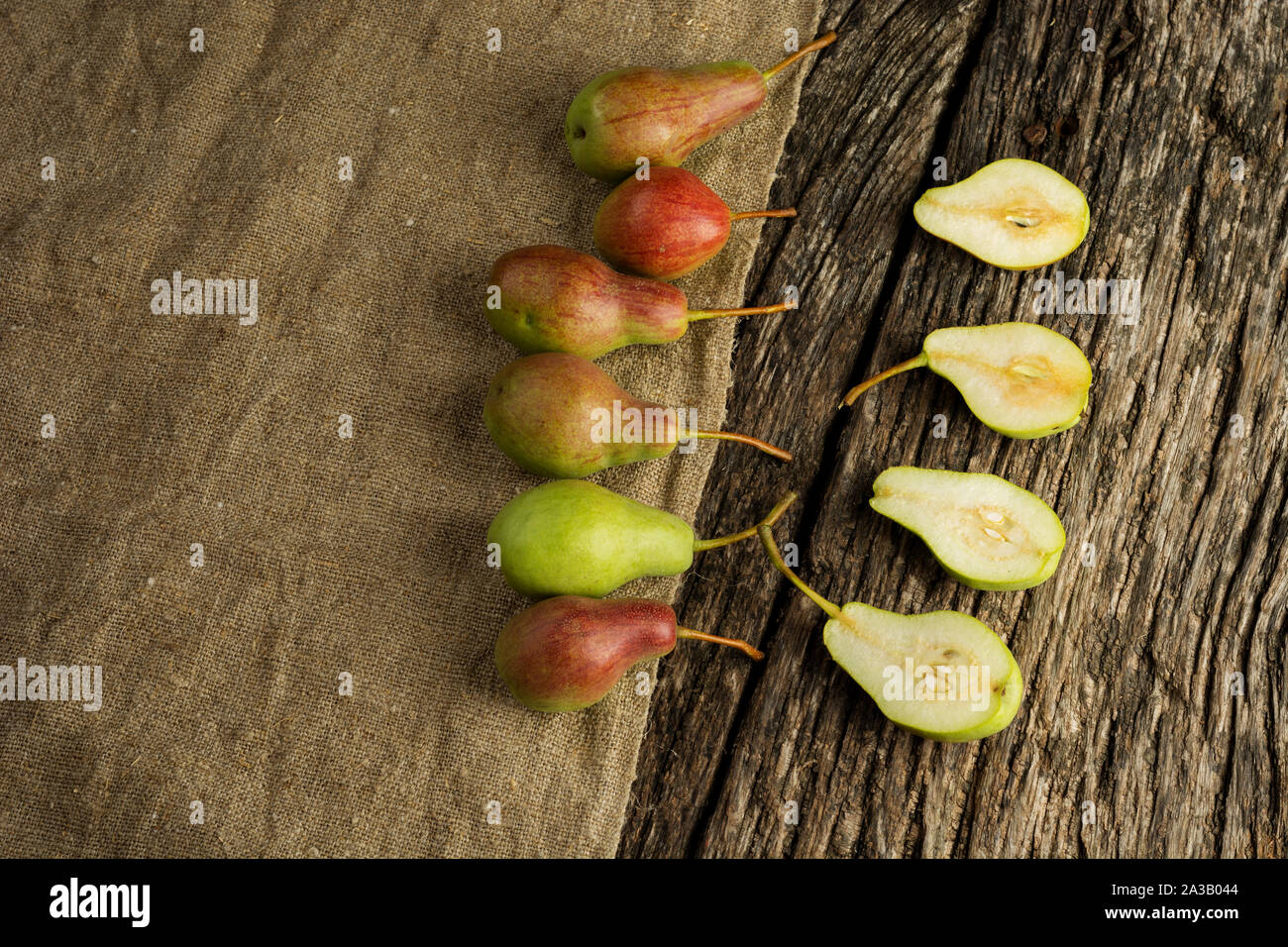 Douce moitié poire juteuse balance avec un fruit entier sur une table en bois rustique, vue d'en haut. Mise à plat. Banque D'Images