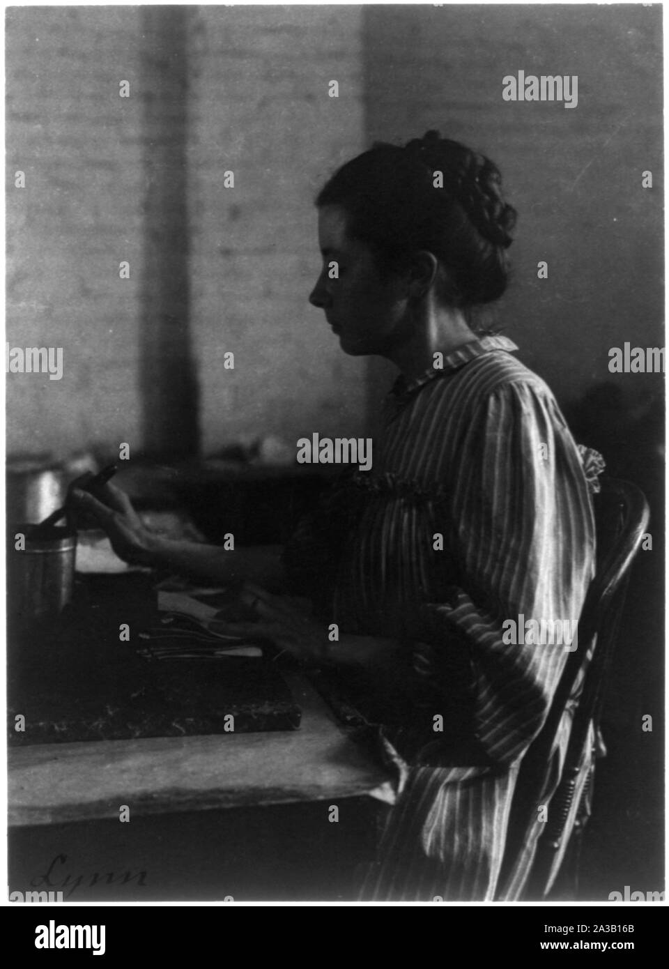 Usines de chaussures, Lynn, Mass. : femme assise à table, travaillant en usine de chaussures Banque D'Images