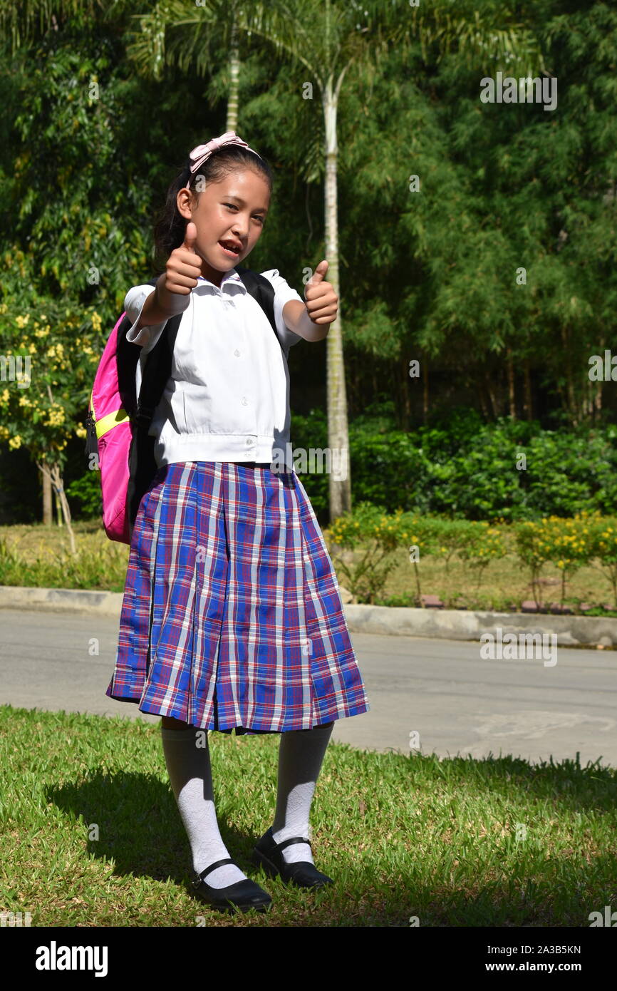School Girl with Thumbs Up portant l'uniforme scolaire avec les ordinateurs portables Banque D'Images