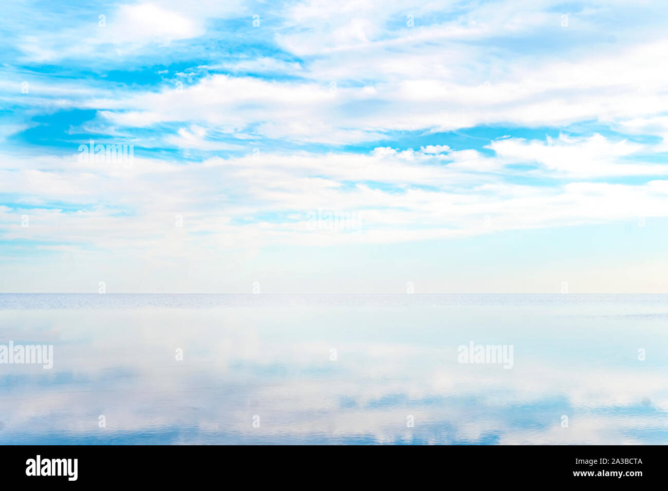 La surface de la mer bleu clair avec ondulations et ciel avec nuages duveteux. d'horizon. Fond de l'eau naturel. Reflet de nuages dans l'eau claire du sel Banque D'Images