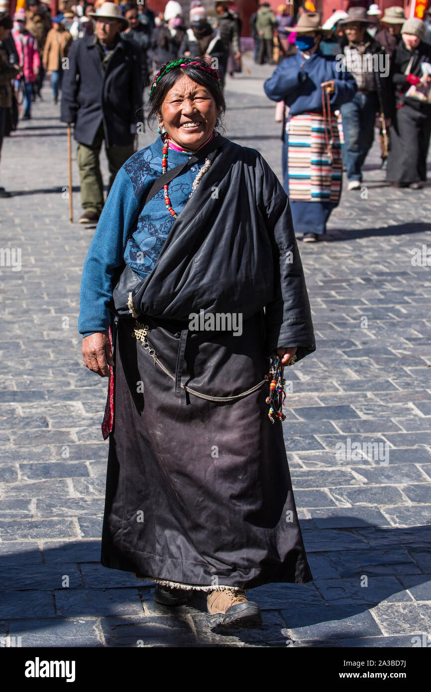 Une vieille femme circumambulates pèlerin tibétain le Temple de Jokhang,  avec son chapelet à Lhassa, au Tibet. Elle est vêtue de son manteau  traditionnel chuba Photo Stock - Alamy