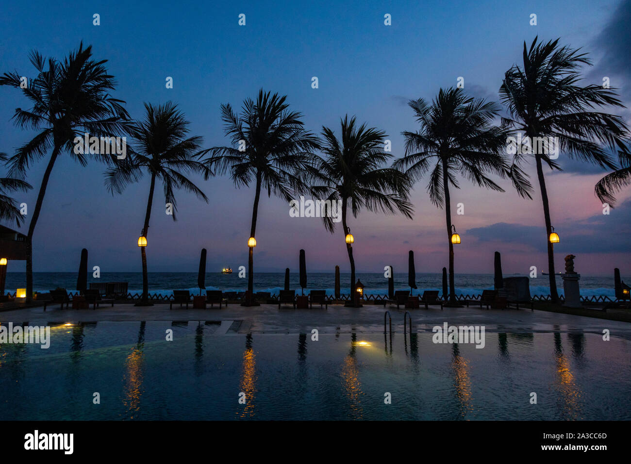 Piscine, palmiers et l'Océan Indien au crépuscule, resort de Candi Dasa ou Candidasa, Bali, Indonésie, Asie Banque D'Images