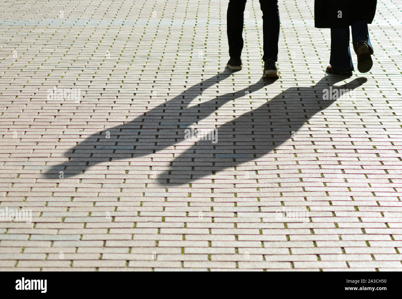 Les jambes et les ombres de personnes sur le pavé Banque D'Images