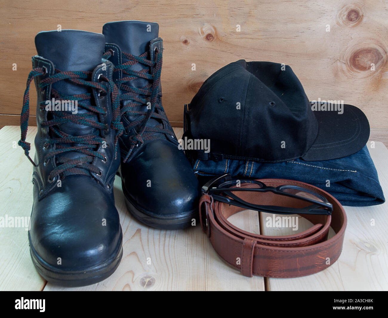 Chaussures, ceintures, chapeau, lunettes de soleil et un jean , placé sur un plancher en bois. Banque D'Images
