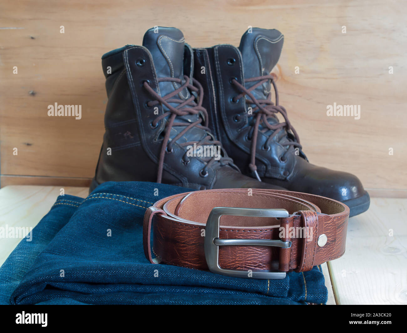 Chaussures, ceintures, jeans , placé sur une table en bois. Banque D'Images