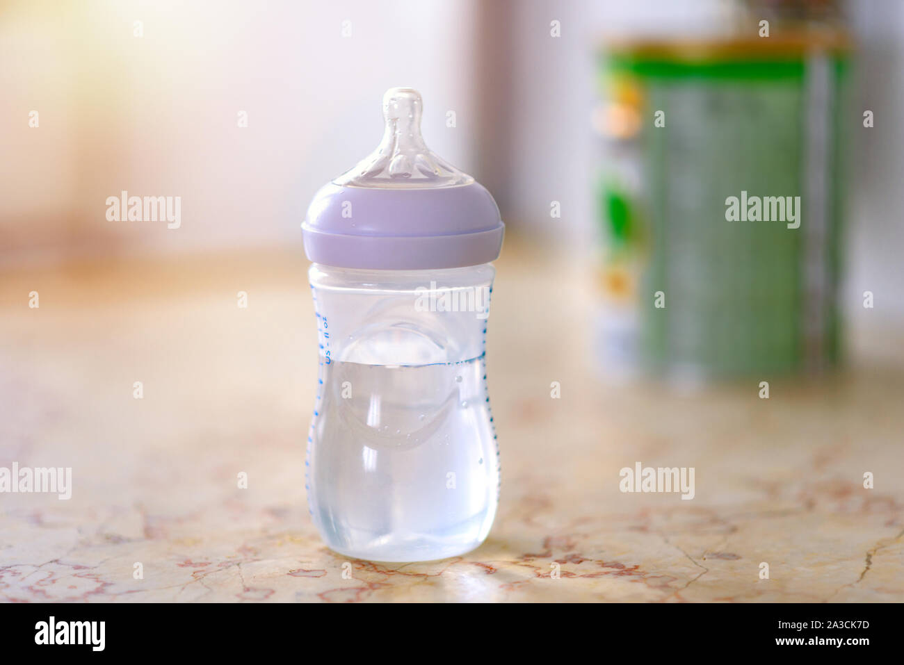Préparation du mélange pour nourrir bébé sur fond de marbre dans la cuisine  le matin avec la lumière du soleil à partir de la fenêtre. Le biberon avec  de l'eau et le