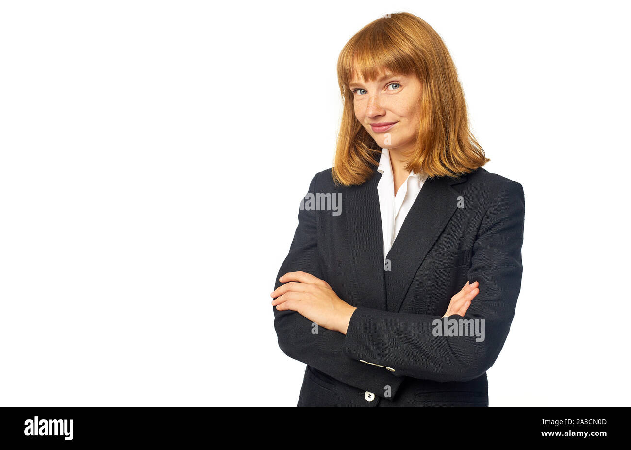 Image of female office worker habillé en chemise blanche et blazer sombre. Femme rousse en vêtements d'affaires regardant la caméra et smiling Banque D'Images