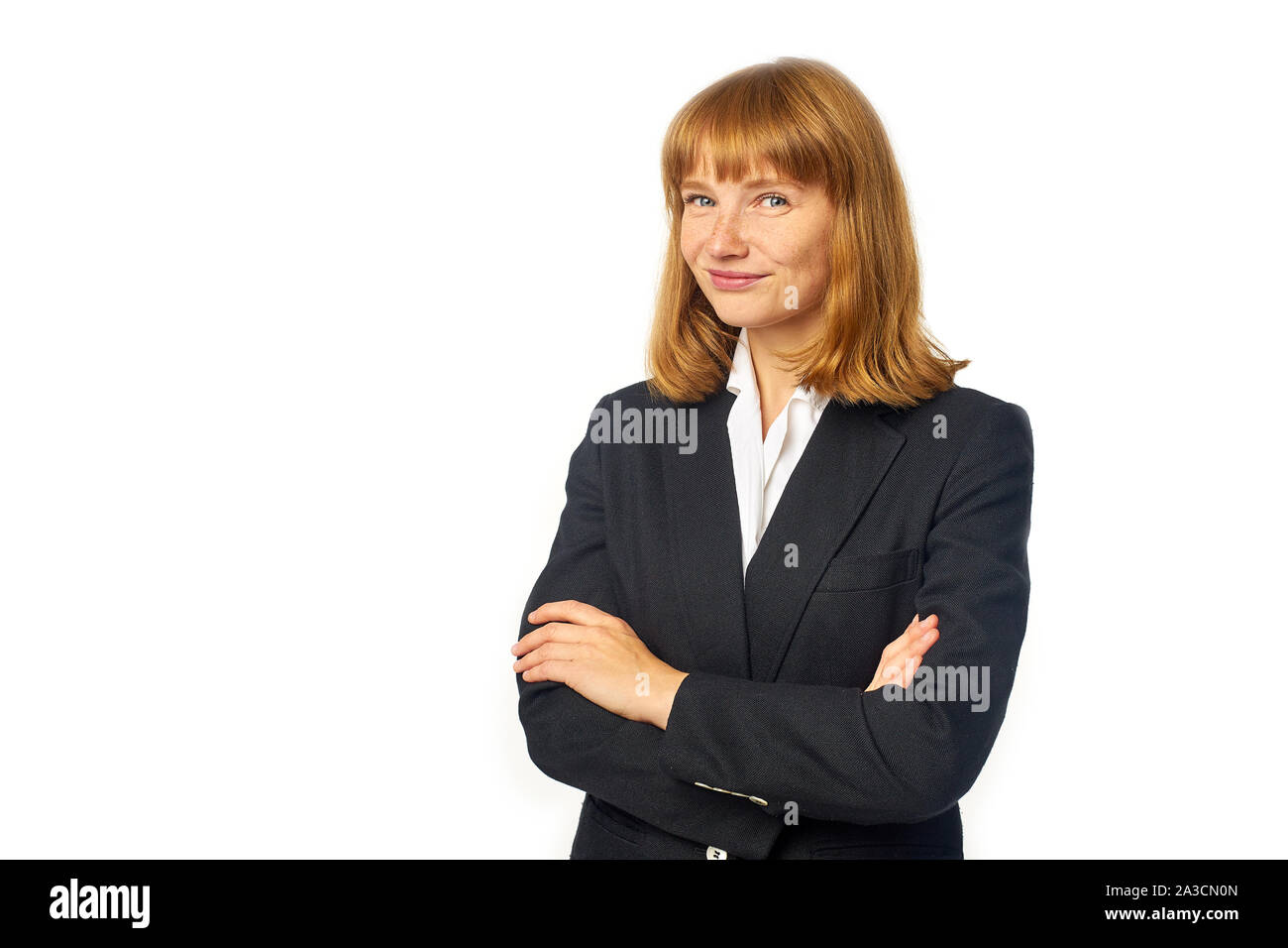 Image of female office worker habillé en chemise blanche et blazer sombre. Femme rousse en vêtements d'affaires regardant la caméra et smiling Banque D'Images
