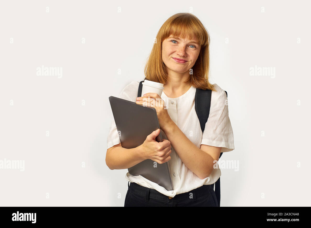 Image de jeune fille rousse avec des taches de rousseur wearing white t-shirt et sac à dos noir regardant la caméra Banque D'Images