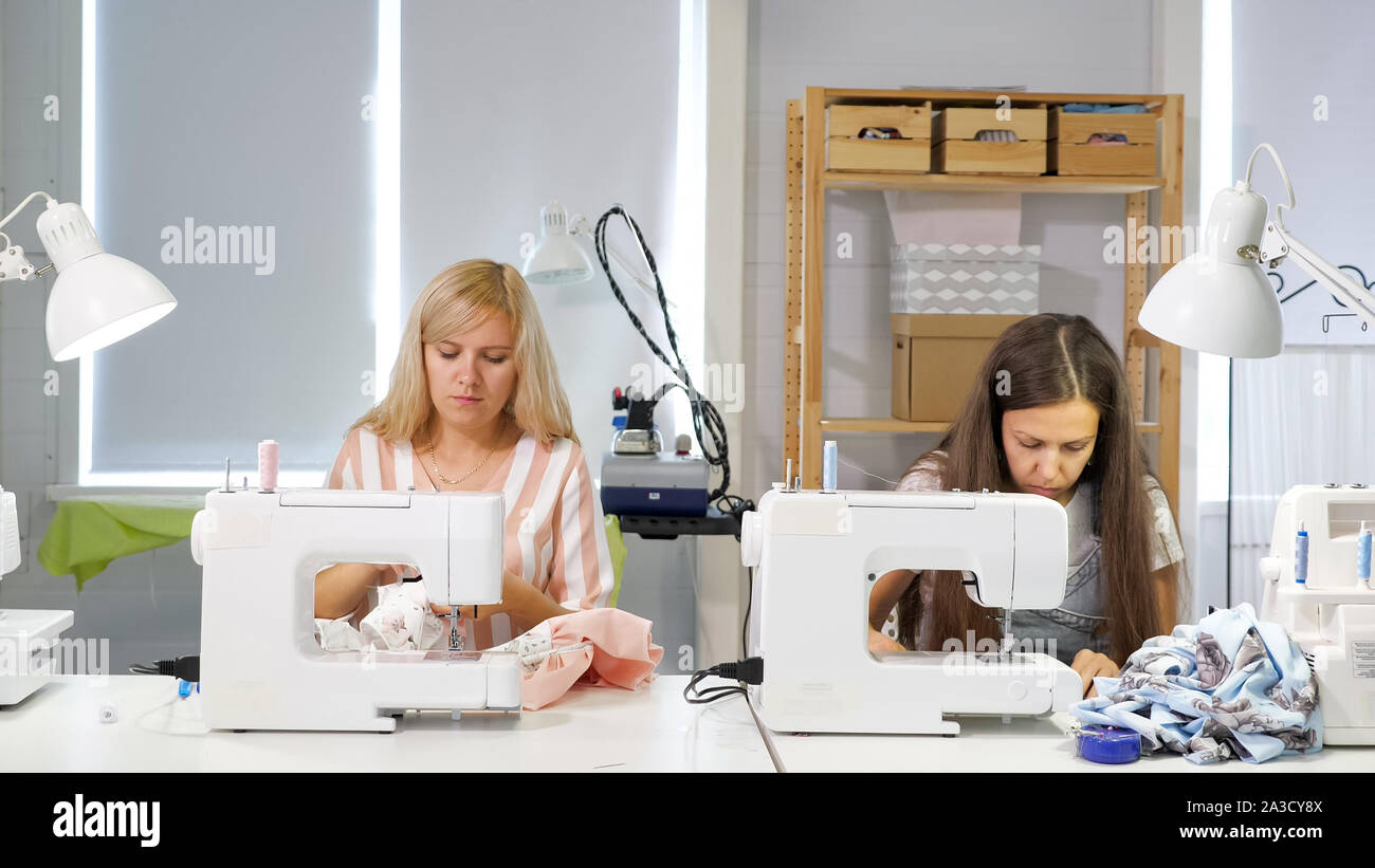 La couture de vêtements. Couturières au travail en atelier sur des vêtements à coudre machine à coudre. Couturière coud des vêtements en atelier. Deux femmes couturière. Couture couture en entreprise. Banque D'Images