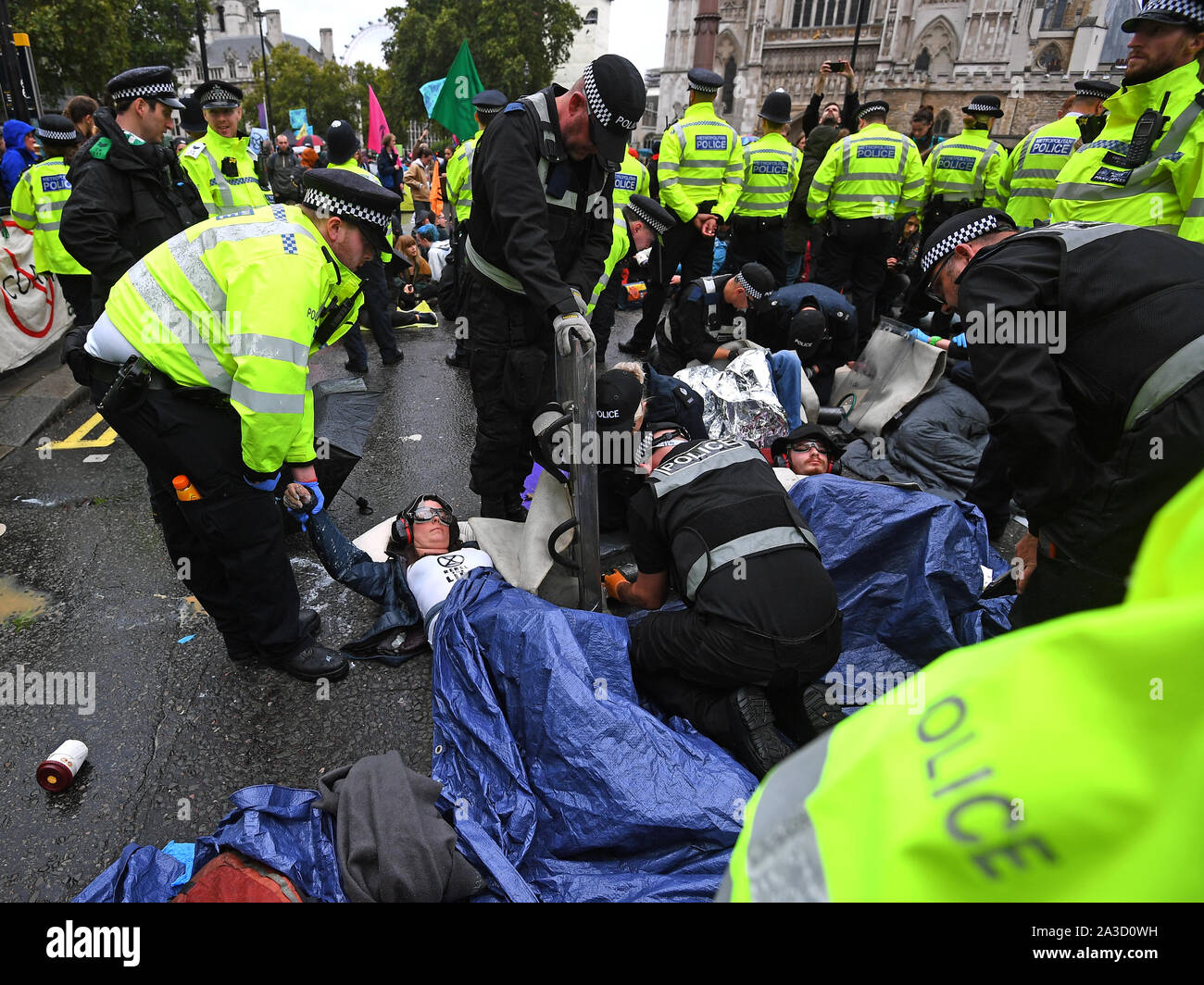 En manifestant par la police, sans coupure, d'où ils sont eux-mêmes enchaînés et collés sur la rue Victoria, à l'extérieur de l'abbaye de Westminster, au cours d'une rébellion d'Extinction (XR) Manifestation à Westminster, Londres. Banque D'Images