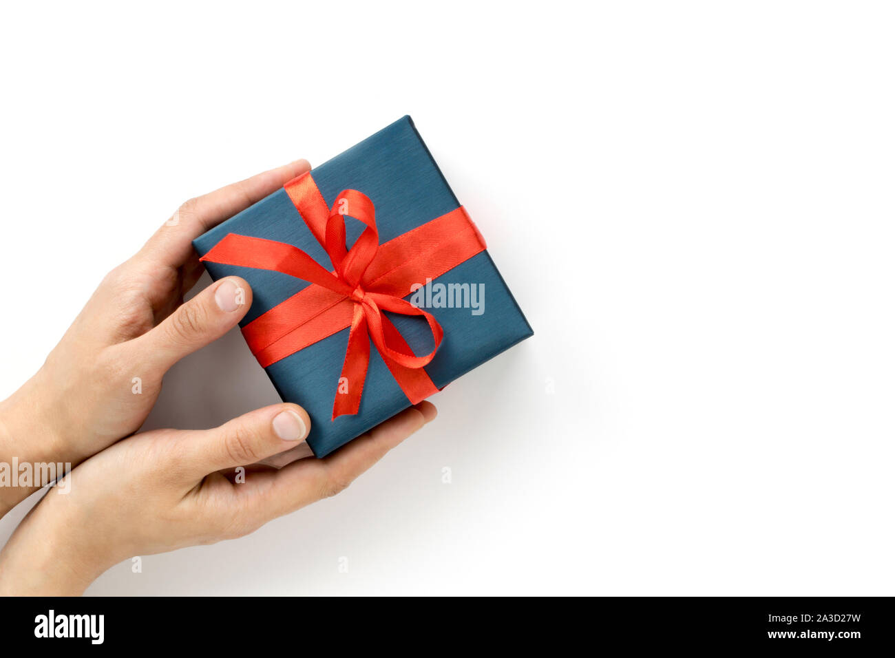Les mains des femmes donnant une boîte cadeau bleu avec ruban rouge sur  fond blanc. Vue d'en haut. Copyspace Photo Stock - Alamy