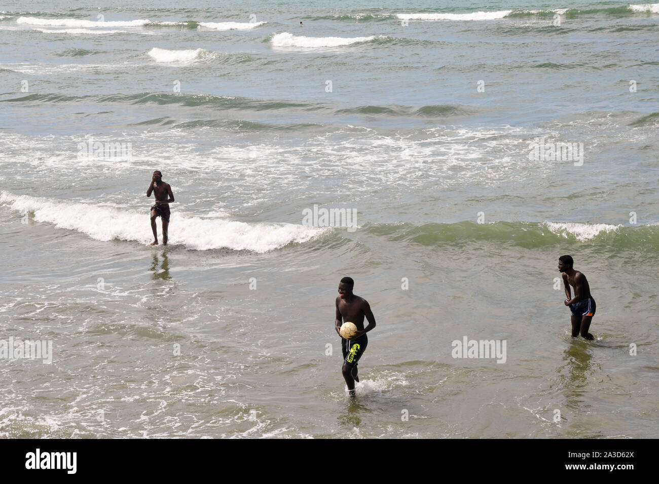 Portrait de trois garçons africains à jouer au ballon sur la plage de Lido di Camaiore dans une journée ensoleillée de la mi-août, la Versilia, Toscane, Italie Banque D'Images