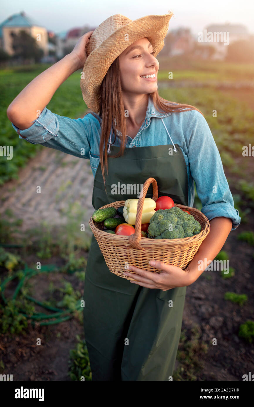 Jardinier cute girl posing on countryside potager avec un panier de légumes Banque D'Images