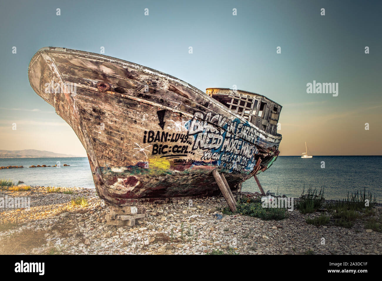 Un vieux bateau de pêche en bois couvert de graffitis sur cale sèche. Banque D'Images