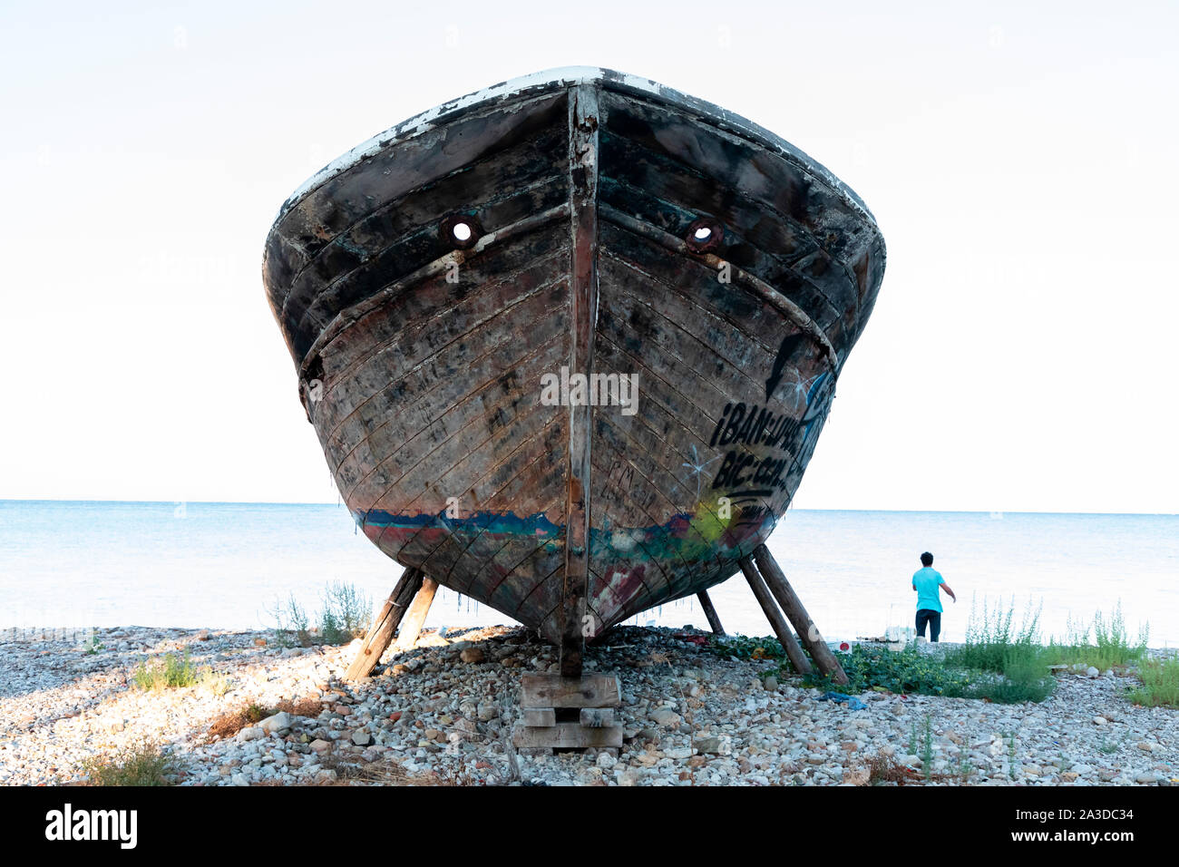 Un vieux bateau de pêche en bois couvert de graffitis sur cale sèche. Banque D'Images