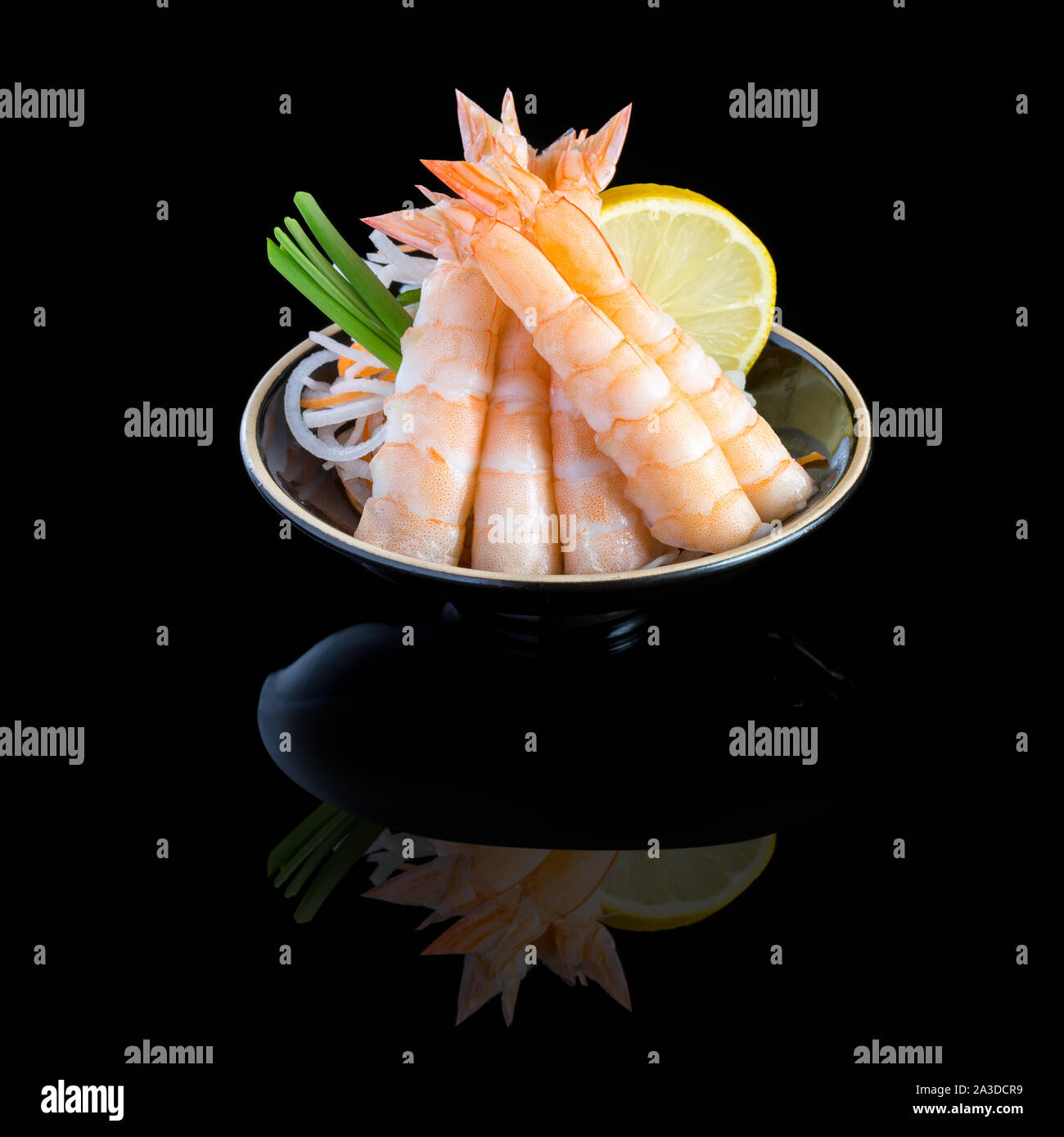 Avec sashimi de crevettes dans une plaque noire. Sur un fond noir avec la réflexion. Banque D'Images