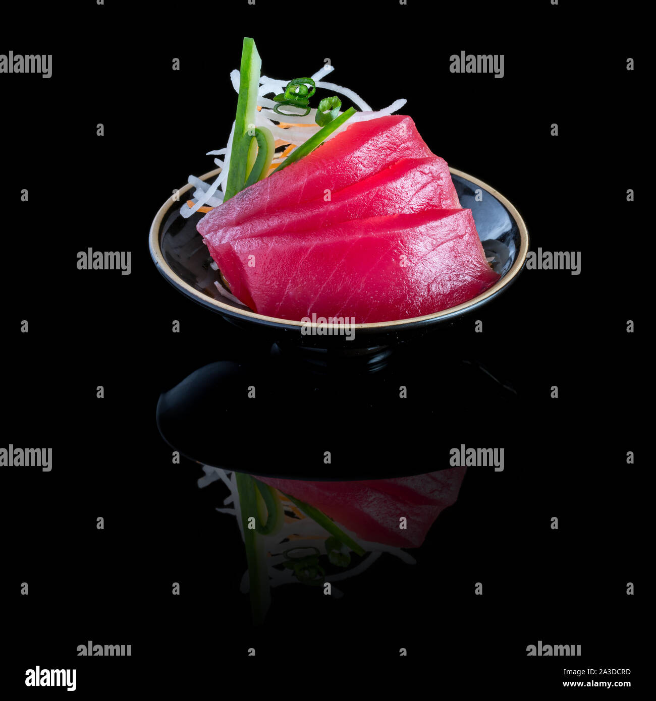Sashimi de thon dans une plaque noire. Sur un fond noir avec la réflexion. Banque D'Images