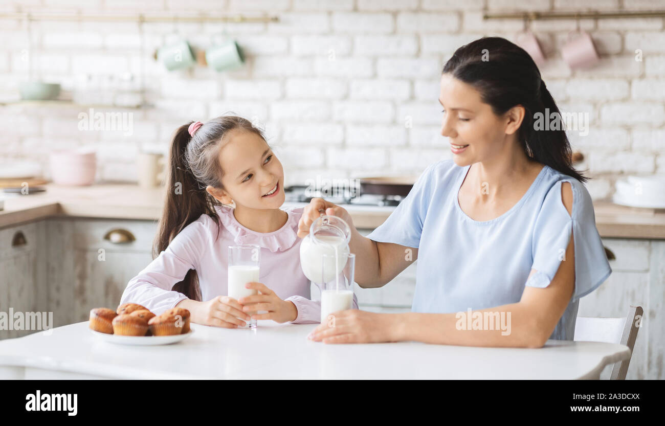 Belle maman et sa fille boire du lait dans la cuisine ensemble Banque D'Images