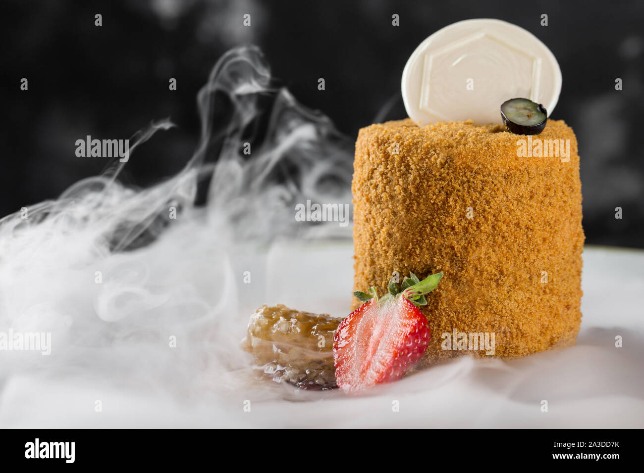 Un classique gâteau au miel. Servi sur une plaque de bois avec de la glace sèche. Banque D'Images