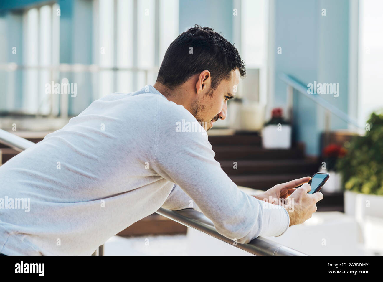 Young man leaning on railing lors de l'utilisation de téléphone mobile Banque D'Images