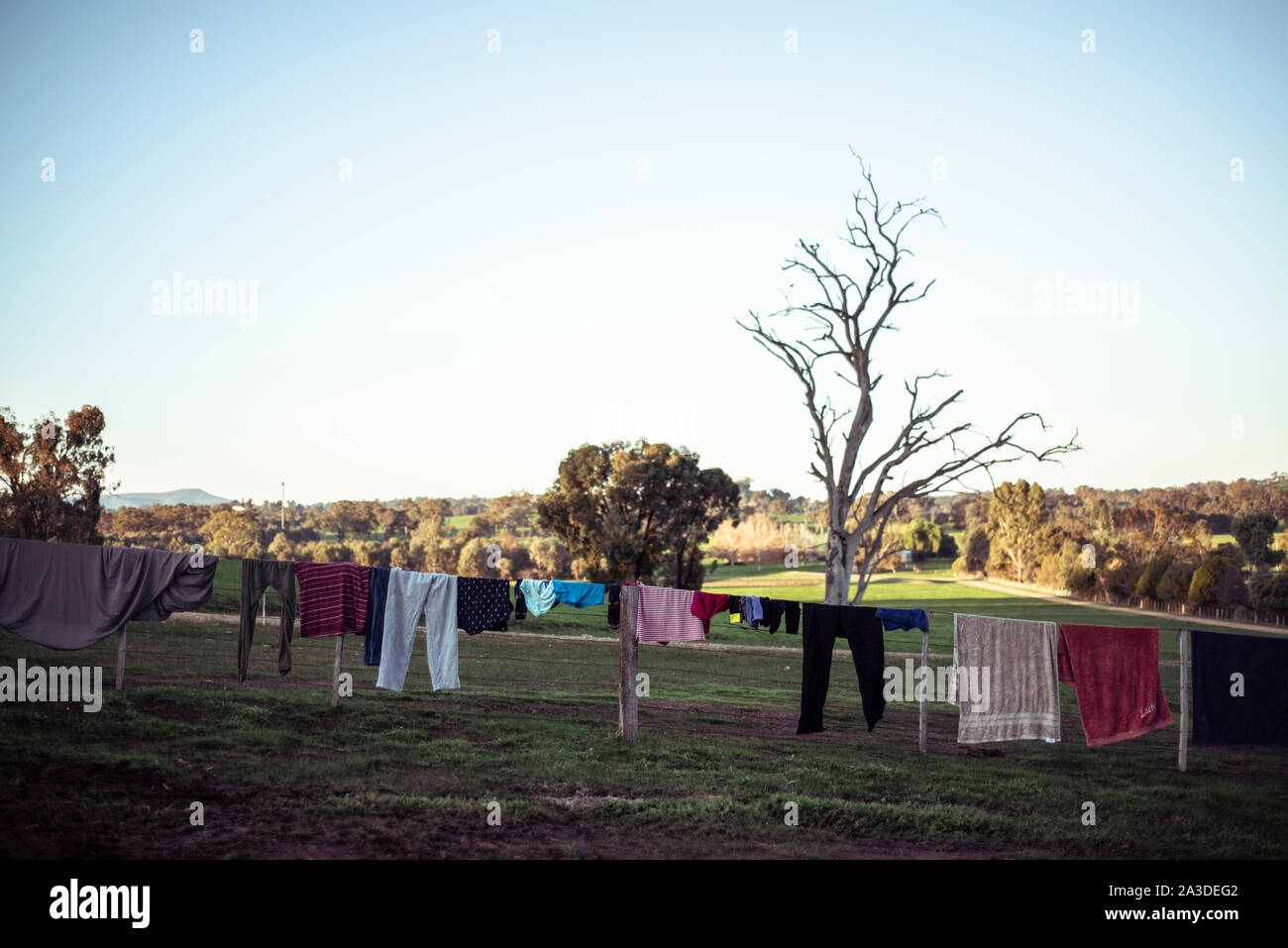 Vêtements sécher sur ligne de clôture comme coucher de soleil sur les terres agricoles en Australie Banque D'Images
