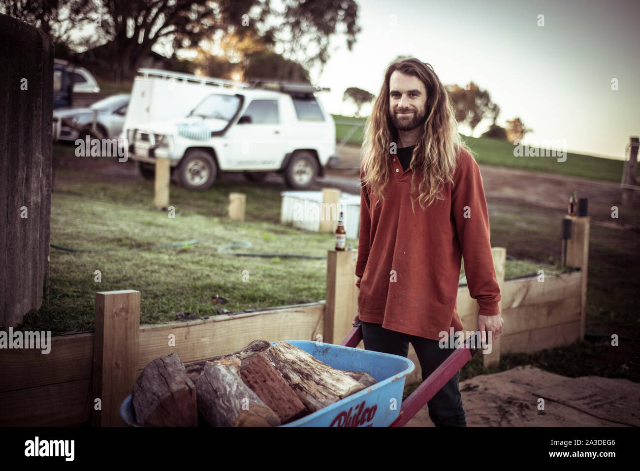 Beau jeune homme avec barbe et cheveux longs à la ferme du bois de pousse Banque D'Images