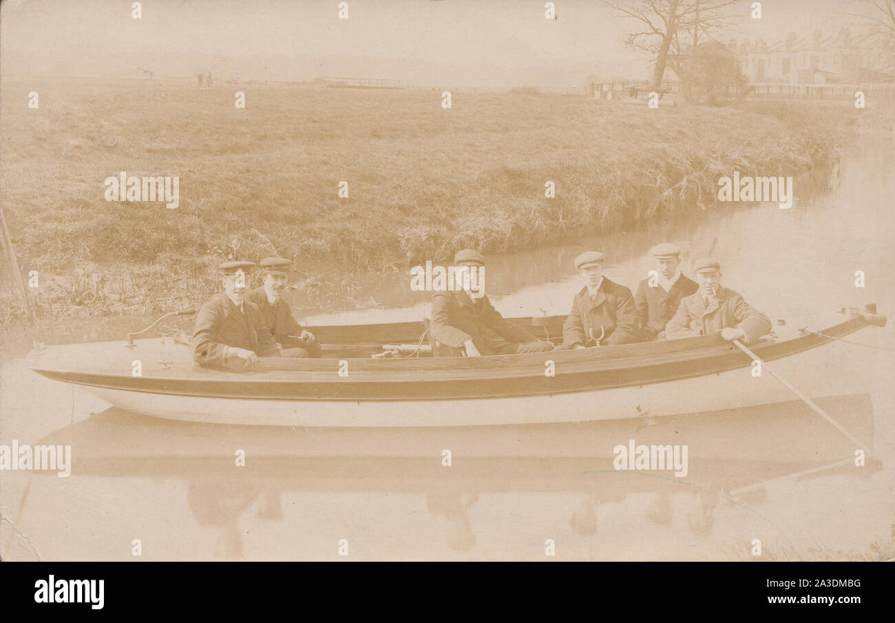 Vintage 1909 traverser Leytonstone Carte postale photographique montrant six hommes dans un bateau à rames. Deux des hommes portant des uniformes. Banque D'Images