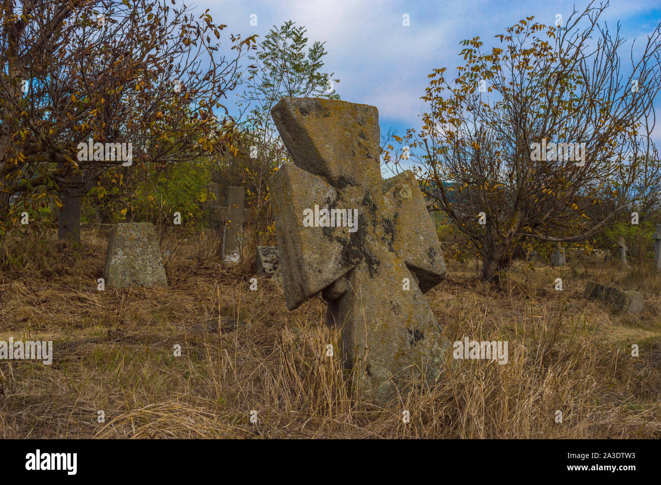 Vieille croix de pierre sur les pierres tombales du cimetière abandonné Banque D'Images