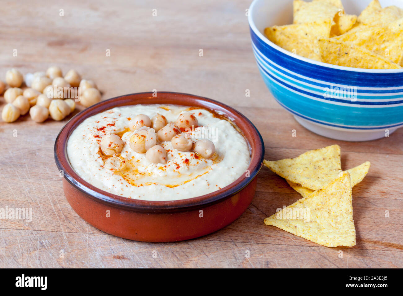 Dip Houmous surmonté de paprika et les pois chiches dans un plat en terre cuite servi avec des croustilles Banque D'Images