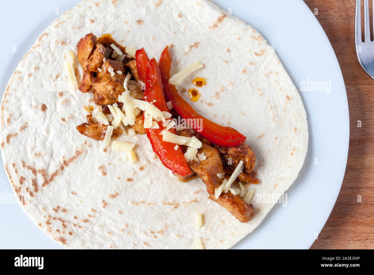 Vue de dessus de chicken fajita mix garni de fromage râpé portant sur une tortilla de farine ouvert Banque D'Images